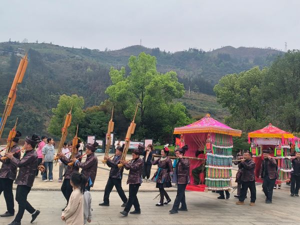 03261774525554469644.jpg 图为 在贵州省从江县北上鼓楼广场,侗族同胞吹奏芦笙,用轿子抬退役军人游行(鲁畅 摄).jpg
